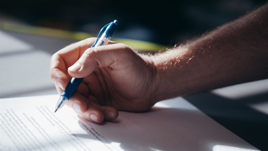 Hand holding a pen over a document