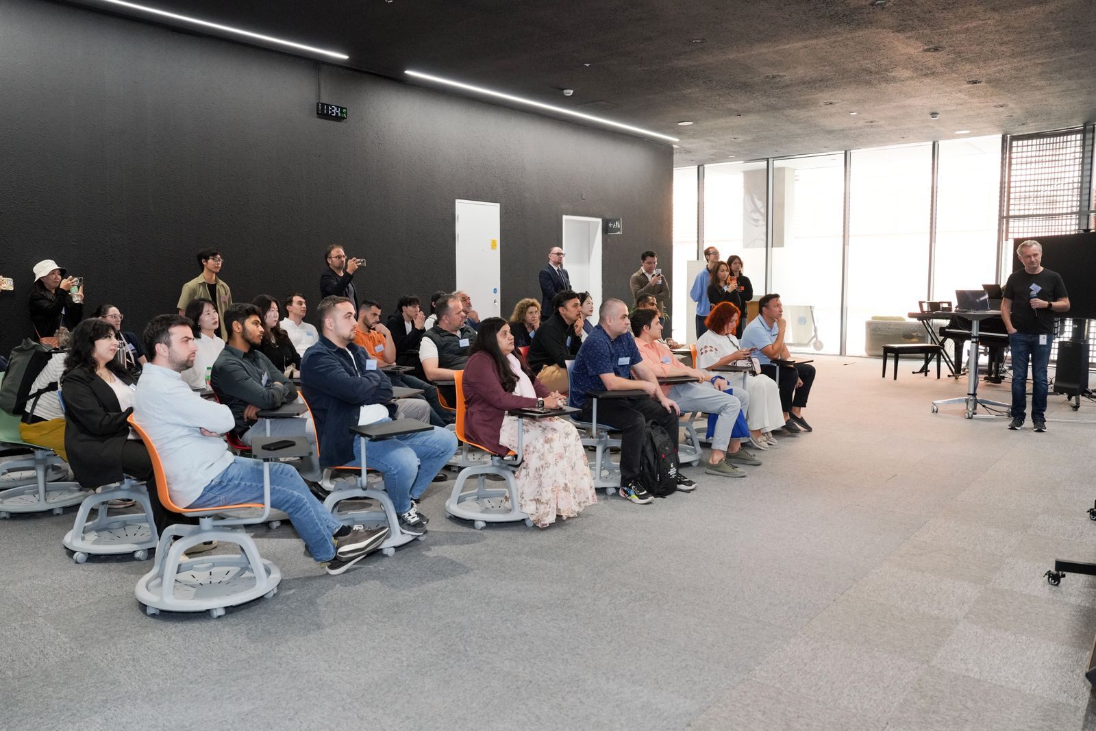 Rows of people seated on chairs listening to a speaker at the front of a large room, the setting of a typical sales presentation